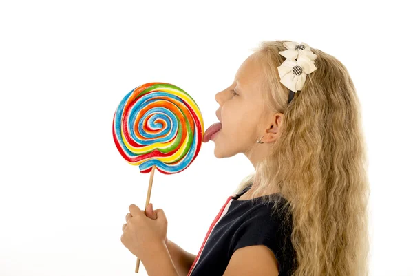 Gyönyörű női gyermek eszik, nyalás, hatalmas spirál nyalóka candy mosolygós boldog hosszú szőke hajjal — Stock Fotó