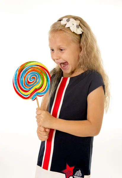 Hermosa hembra niño con largo pelo rubio comer lamiendo enorme espiral piruleta caramelo sonriendo feliz — Foto de Stock