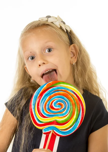 Mooie vrouwelijke kind met lang blond haar eten likken enorme spiraal lollipop snoep glimlachend gelukkig — Stockfoto