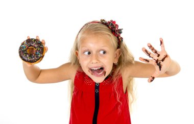 beautiful female child with blue eyes in cute red dress eating chocolate donut with syrup stains