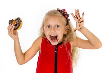 beautiful female child with blue eyes in cute red dress eating chocolate donut with syrup stains
