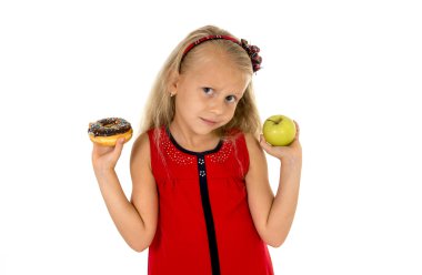 little beautiful blond child choosing dessert holding unhealthy chocolate donut and apple fruit
