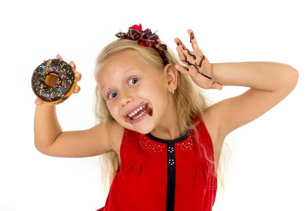 Belle enfant femelle aux yeux bleus dans une jolie robe rouge mangeant un beignet au chocolat avec des taches de sirop — Photo