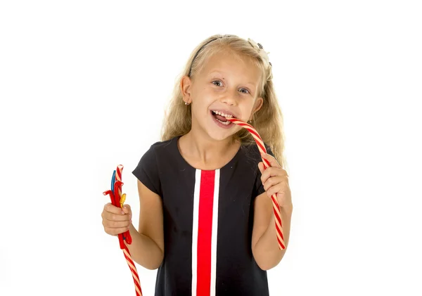 Beautiful little female child with blue eyes eating strawberry licorice candy — Stockfoto