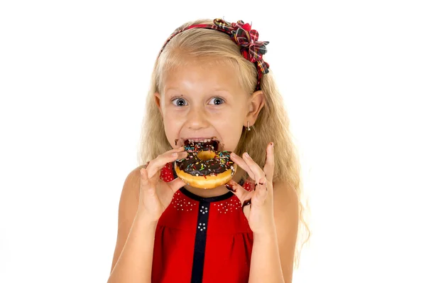 Belle enfant femelle aux yeux bleus dans une jolie robe rouge mangeant un beignet au chocolat avec des taches de sirop — Photo