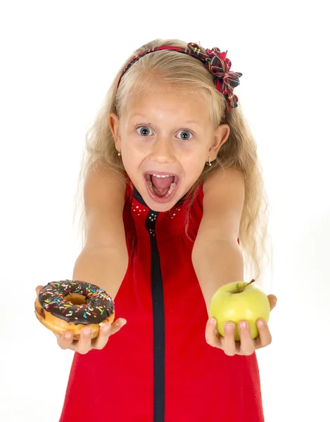 Little beautiful blond child choosing dessert holding unhealthy chocolate donut and apple fruit — ストック写真