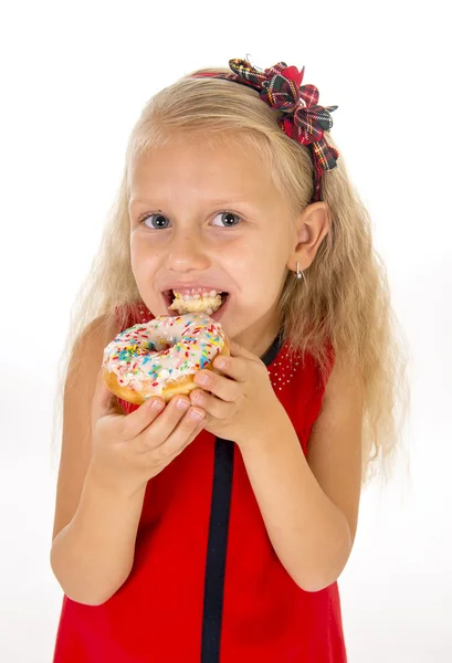 Little beautiful female child with long blonde hair and red dress eating sugar donut with toppings delighted and happy — ストック写真