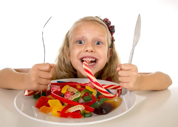 Pretty happy Caucasian female child eating dish full of candy in sweet sugar abuse dangerous diet — Stok fotoğraf