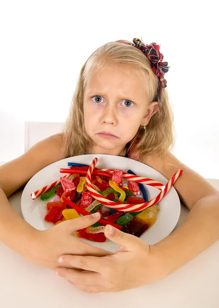 Pretty sad Caucasian female child eating dish full of candy in sweet sugar abuse dangerous diet — Stock Fotó