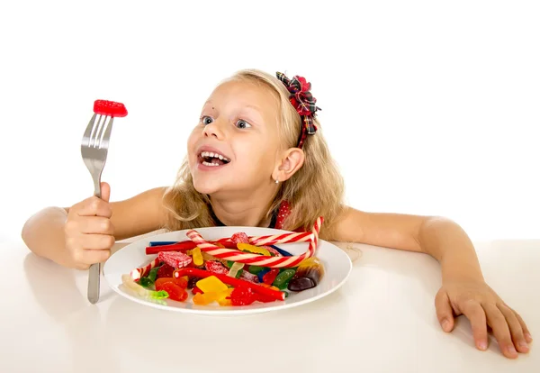 Pretty happy Caucasian female child eating dish full of candy in sweet sugar abuse dangerous diet — Stock fotografie