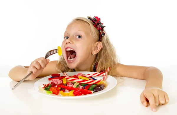 Pretty happy Caucasian female child eating dish full of candy in sweet sugar abuse dangerous diet — Stok fotoğraf