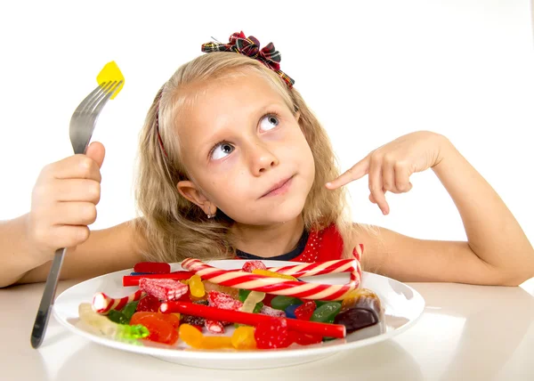 Pretty happy Caucasian female child eating dish full of candy in sweet sugar abuse dangerous diet — Stock fotografie