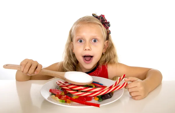 Pretty happy Caucasian female child eating dish full of candy in sweet sugar abuse dangerous diet — стокове фото