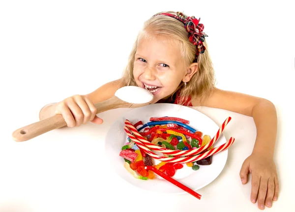 Pretty happy Caucasian female child eating dish full of candy in sweet sugar abuse dangerous diet — стокове фото