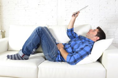 young attractive 30s man using digital tablet pad lying on couch at home networking looking relaxed