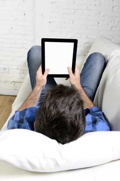 Man lying on home couch using digital tablet pad in portable internet technology — Stok fotoğraf