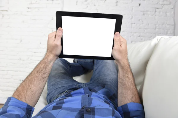 Man lying on home couch using digital tablet pad in portable internet technology — ストック写真