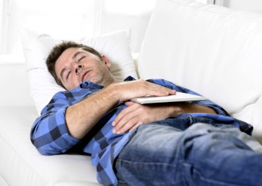 young attractive man sleeping at home couch relaxing after working with digital tablet pad