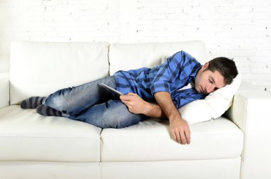 young attractive man sleeping at home couch relaxing after working with digital tablet pad