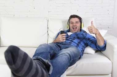 20s or 30s man having fun listening to music with mobile phone and headphones