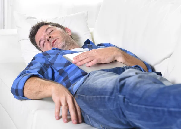 Young attractive man sleeping at home couch relaxing after working with digital tablet pad — Stok fotoğraf