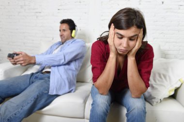 woman  angry and upset while husband or boyfriend plays videogames ignoring her