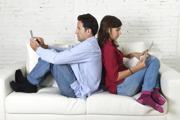 Couple on couch ignoring each other using mobile phone and digital tablet in internet addiction — Zdjęcie stockowe