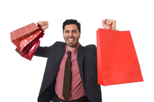 Jovem atraente empresário segurando um monte de sacos de compras em estresse isolado no fundo branco — Fotografia de Stock
