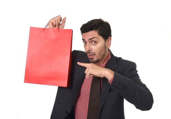 Young attractive businessman holding and pointing red shopping bag in sale concept performing as salesman — Zdjęcie stockowe