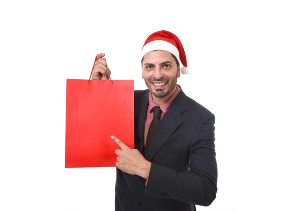 Jovem atraente empresário no Natal Santa chapéu segurando e apontando saco de compras vermelho em dezembro e venda de ano novo — Fotografia de Stock