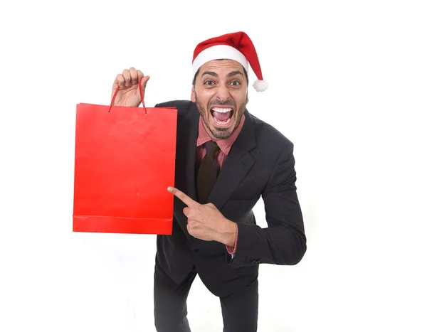 Funny businessman in Christmas Santa hat holding red shopping bag in December and New year sale — Zdjęcie stockowe