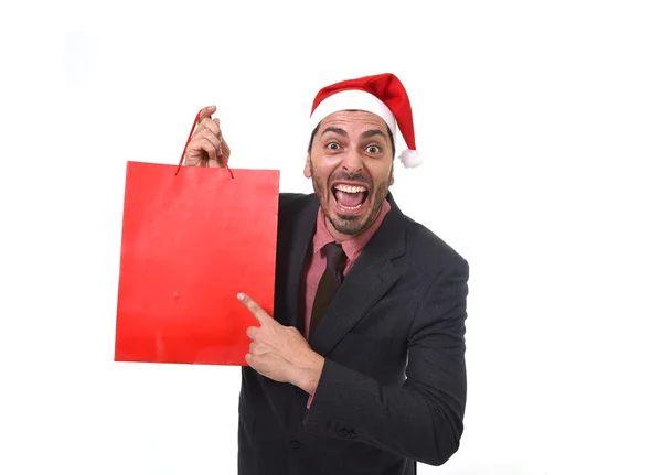 Funny businessman in Christmas Santa hat holding red shopping bag in December and New year sale — ストック写真
