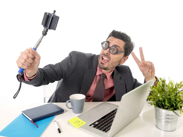 Funny nerd businessman at office desk taking selfie photo with mobile phone camera and stick — 图库照片