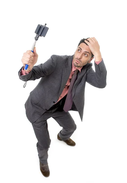 Joven atractivo hombre de negocios en traje y corbata tomando foto selfie con la cámara del teléfono móvil y palo posando feliz — Foto de Stock