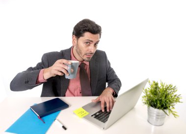 young attractive Latin businessman in suit and tie working at office computer desk drinking cup of coffee