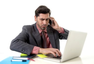 busy businessman working in stress on computer laptop talking on mobile phone