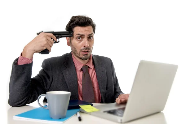 Бизнесмен в офисе работает на компьютере ноутбук указывая пистолет темп в жесте самоубийства — стоковое фото