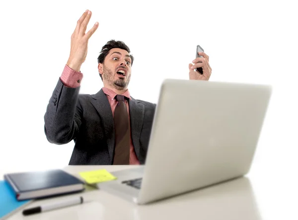 Attractive businessman sitting at office desk working in stress on computer laptop talking on mobile phone overworked — ストック写真