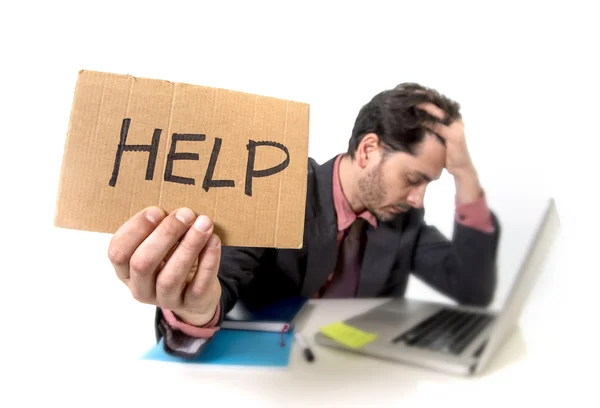 Homme d'affaires en costume et cravate assis au bureau de travail sur ordinateur portable demandant de l'aide tenant signe de carton — Photo
