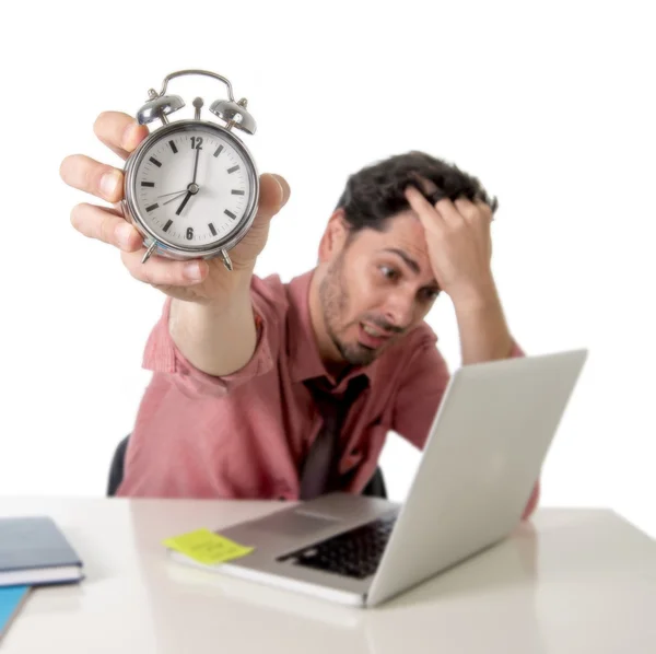 Depressed businessman holding alarm clock sitting at office desk working with computer laptop in deadline project concept — Stockfoto