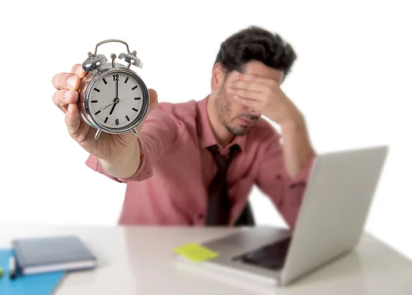 Depressed businessman holding alarm clock sitting at office desk working with computer laptop in deadline project concept — Zdjęcie stockowe