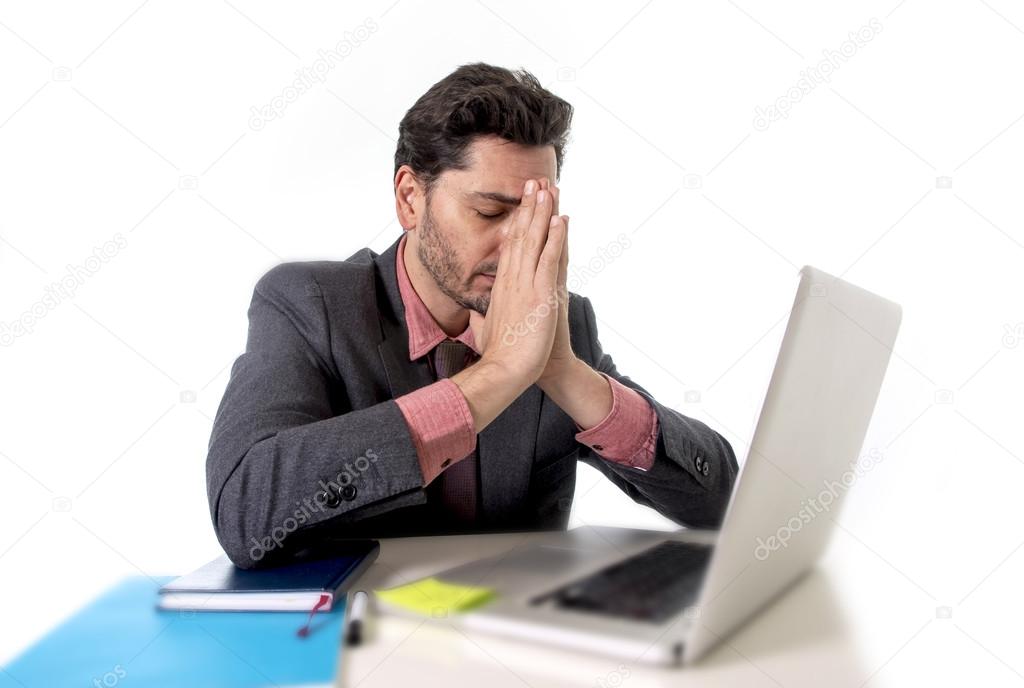 young businessman sitting at office desk working on computer laptop desperate worried in work stress
