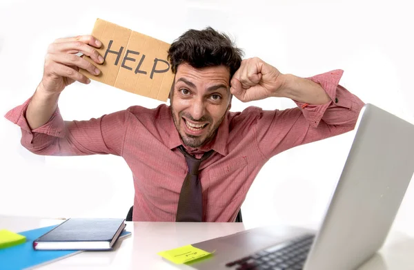 Hombre de negocios en el escritorio de la oficina trabajando en computadora portátil pidiendo ayuda sosteniendo cartel de cartón buscando triste y deprimido — Foto de Stock