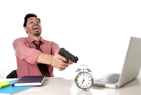 Homem de negócios em estresse na mesa do computador do escritório apontando pistola de mão para despertador em fora do tempo e prazo do projeto expirando — Fotografia de Stock