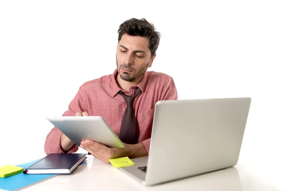 Hombre de negocios que trabaja en el escritorio de la oficina usando tableta digital que se sienta delante de la computadora portátil que mira ocupado — Foto de Stock