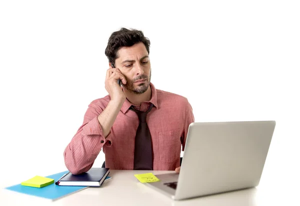 Homem de negócios atraente trabalhando na mesa de escritório mensagens de texto com telefone celular na frente do laptop de computador parecendo ocupado — Fotografia de Stock