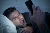 Mann im Bett Couch zu Hause spät in der Nacht mit Handy in niedrigen