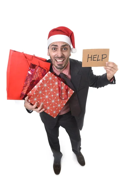 Hombre de negocios en Santa Claus sombrero sosteniendo bolsas de compras pidiendo ayuda con cartel de cartón preocupado —  Fotos de Stock