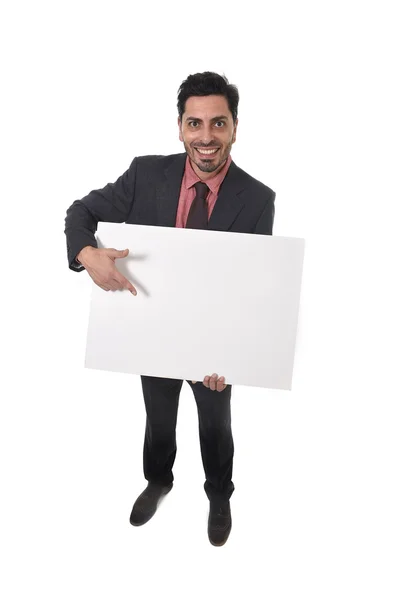 Joven atractivo hombre de negocios en traje y corbata sosteniendo y señalando cartelera blanca en blanco o panel publicitario —  Fotos de Stock