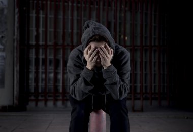 sad woman alone on street suffering depression desperate and helpless wearing hoodie